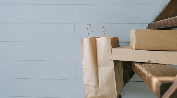 A flat lay of modern eco friendly paper packaging boxes and bags with recycling icons EPR compliance checklist and a laptop showing sustainability analytics dashboard