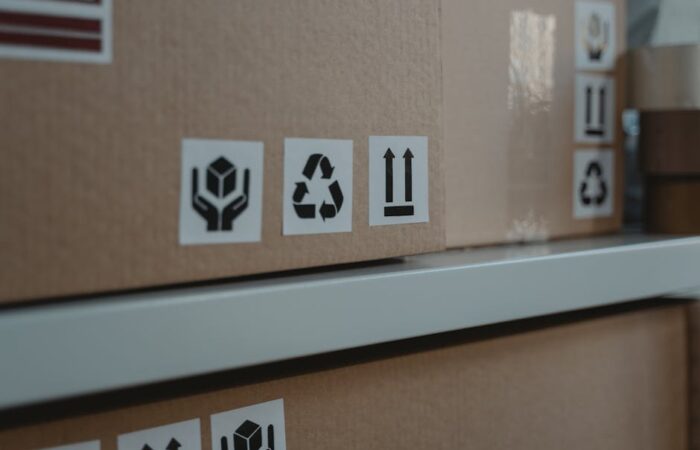 A modern warehouse packing line with branded sustainable paper boxes and bags overlaid with icons showing recycling compliance checklists and a US map of states with EPR laws