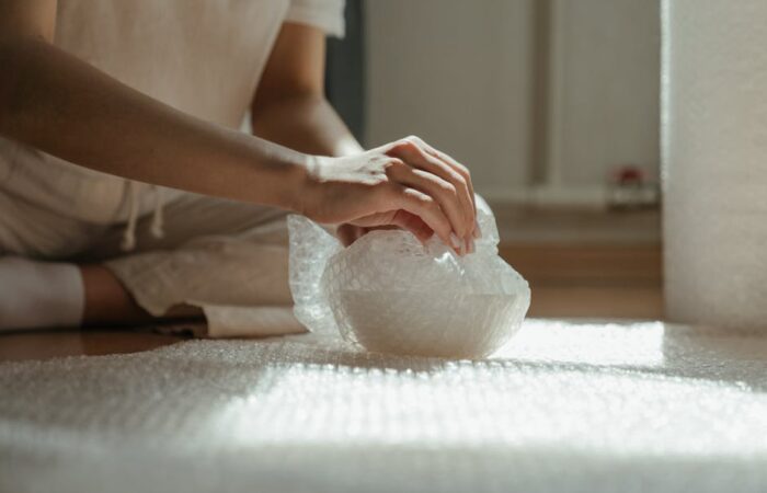 Close up of fragile glassware wrapped in white Curby Fragile Wrap paper cushioning inside a custom corrugated box showing honeycomb texture and secure fit